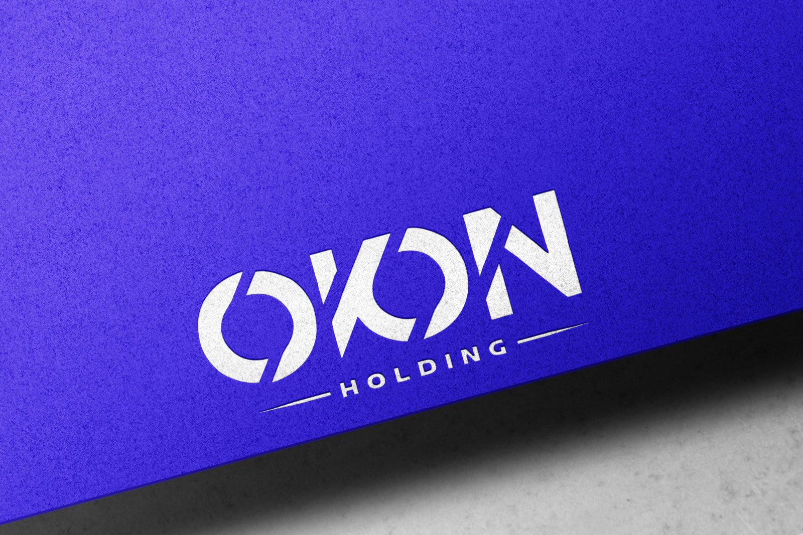 Mavi doku üzerinde beyaz kabartma OKON Holding logosu